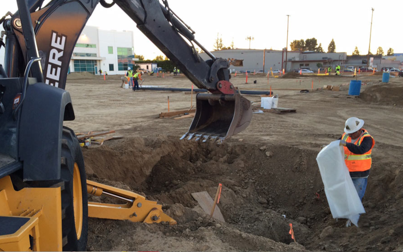Excavator removing impacted soil from an open excavation.